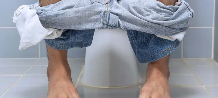 Mans legs with a toilet behind him