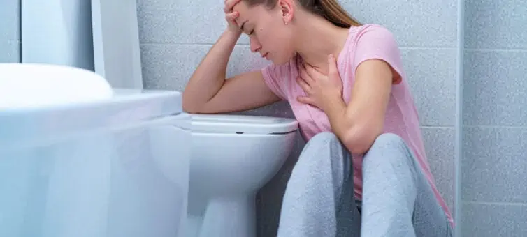 Woman sitting by the toilet with nausea
