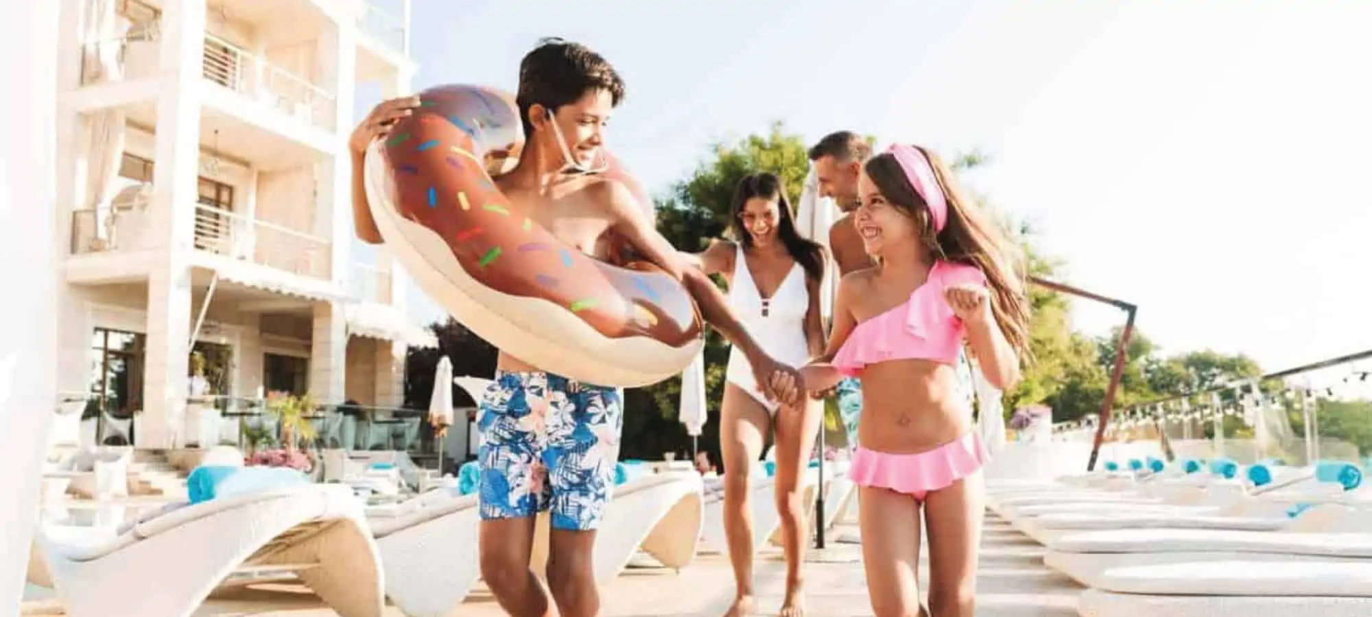 Kids running outside with pool floaties on vacation
