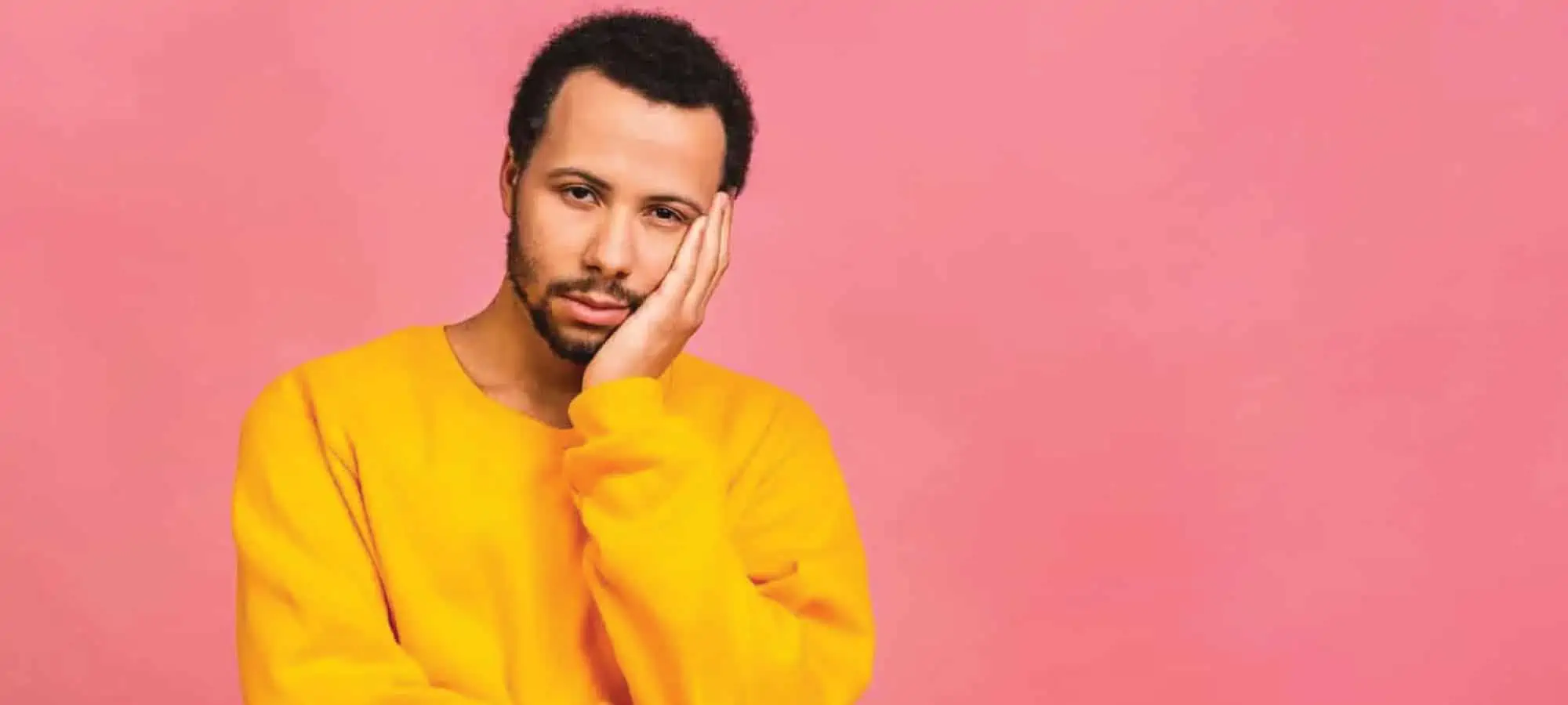 Person sad with hand on face pink background