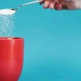 Putting sugar into a cup of coffee