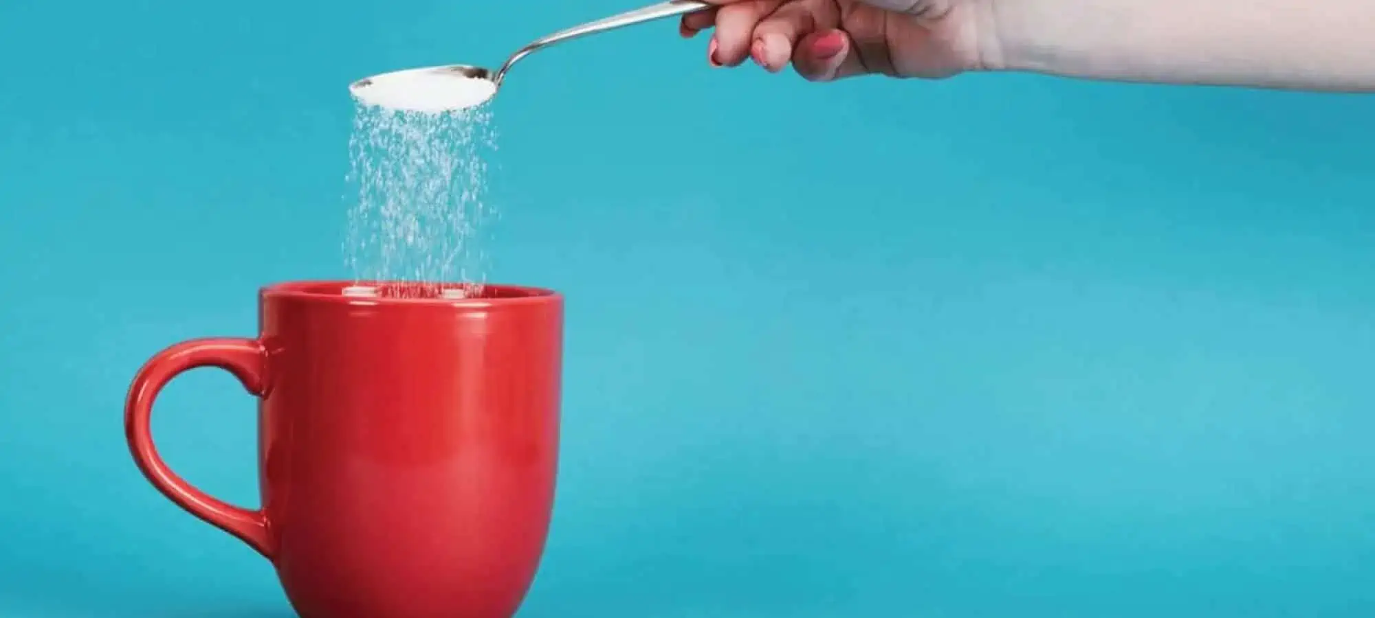Putting sugar into a cup of coffee