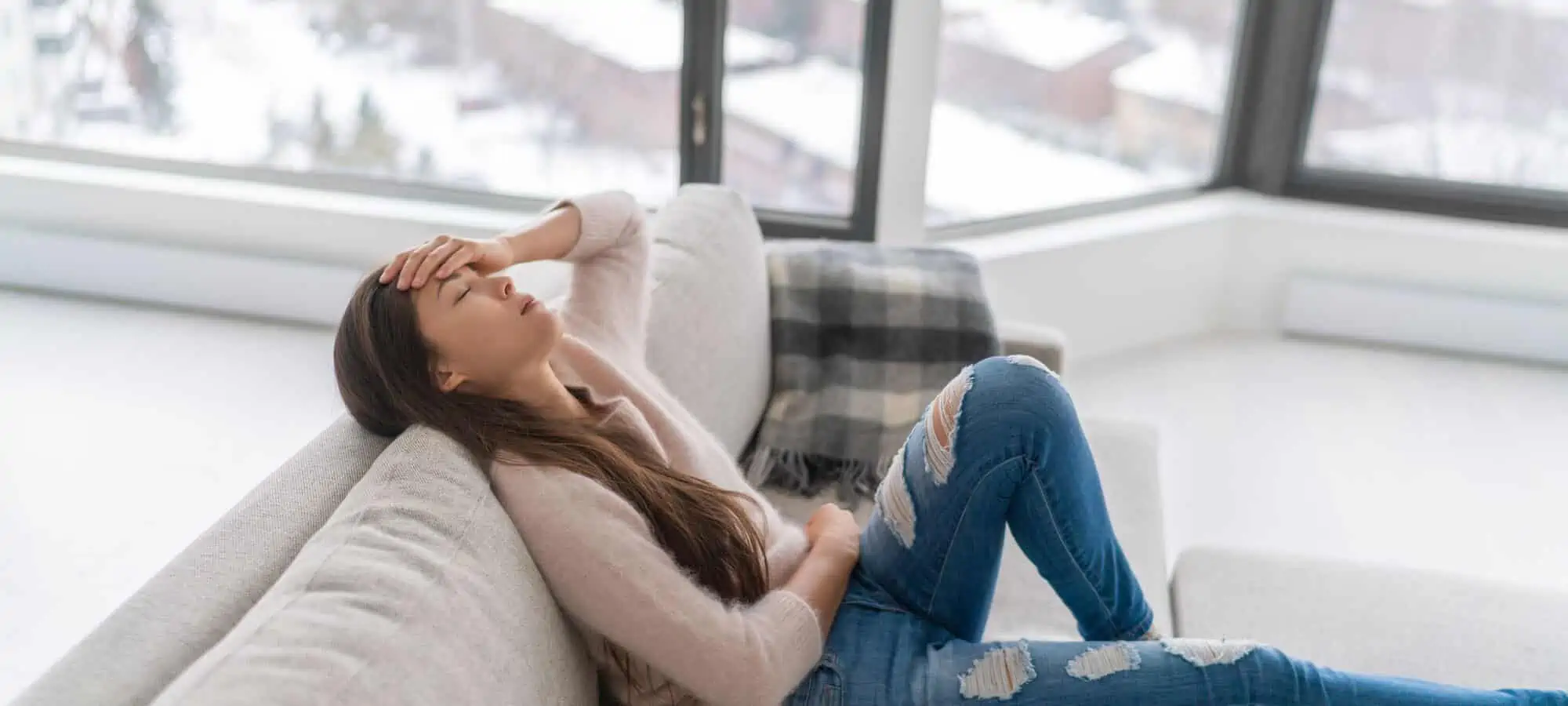 Young woman lying on couch in pain