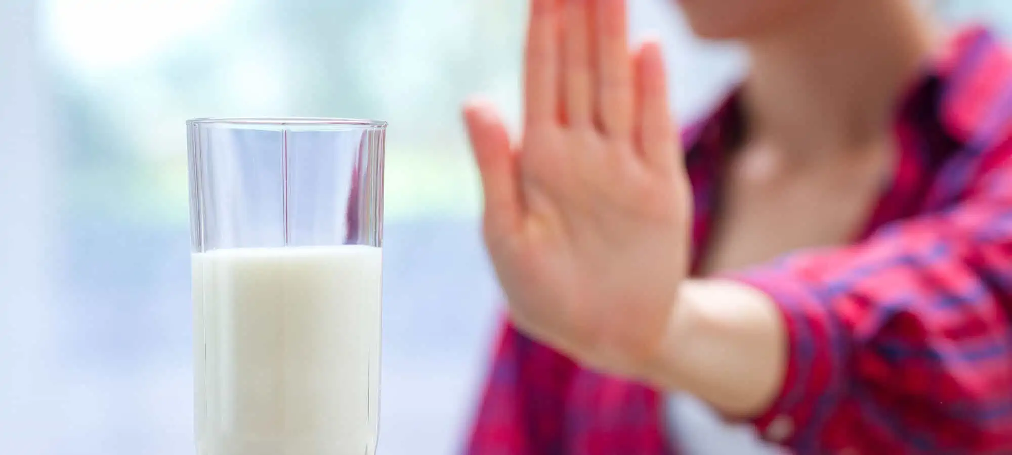 Young woman saying no to a glass of milk
