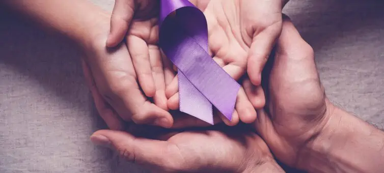 hands of a man, woman and child holding a purple ribbon for pancreatic cancer