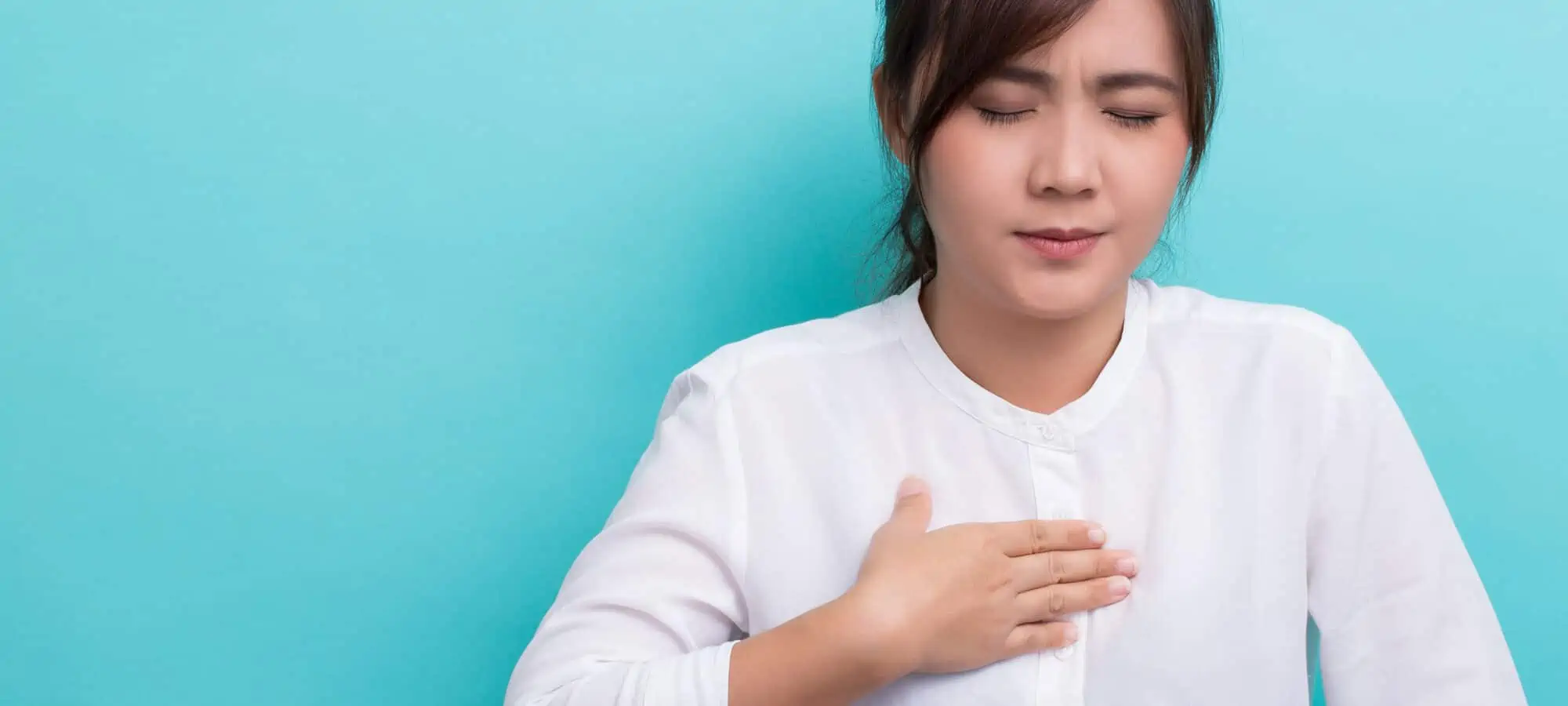 Young asian woman clutching chest in pain