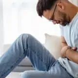 Man clenching stomach on the couch