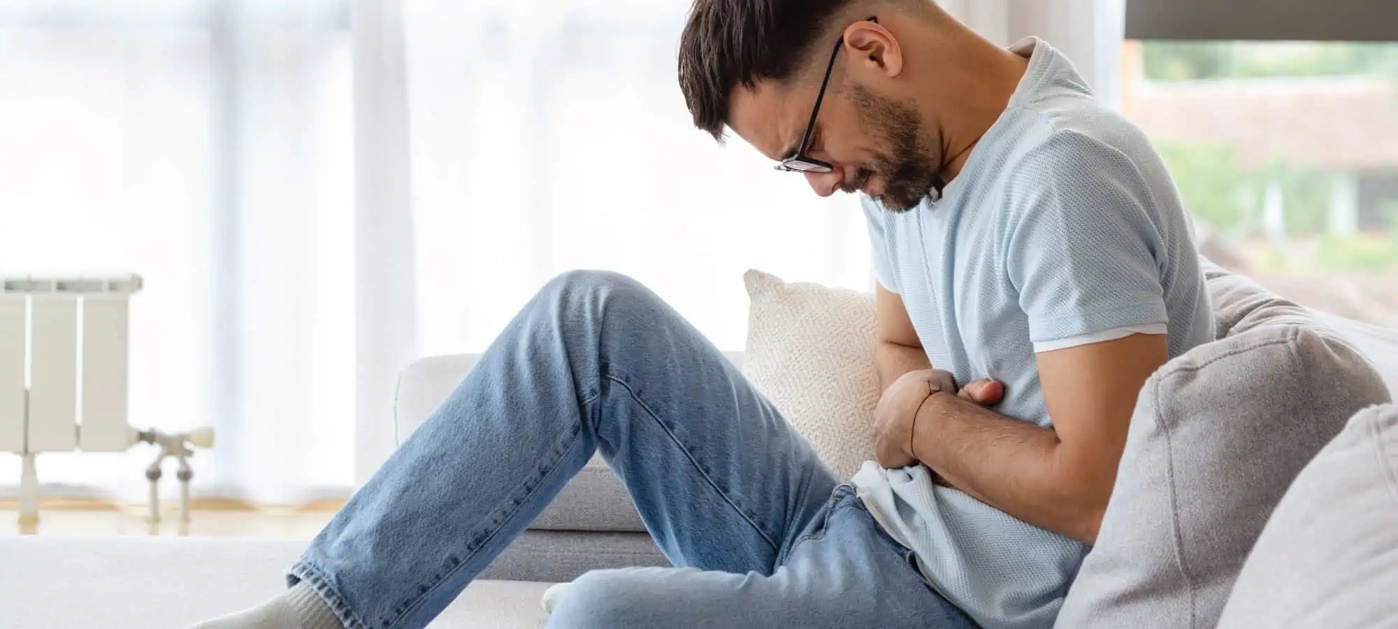 Man clenching stomach on the couch