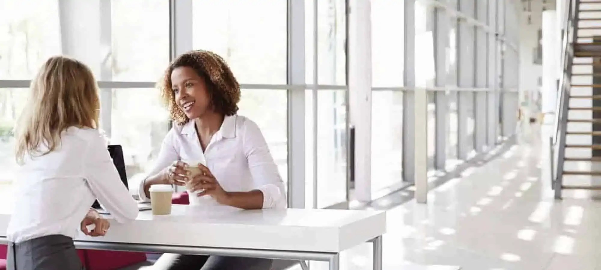 Women talking to another women in an office with a lot of windows
