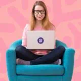 Woman in chair reading her laptop and smiling