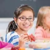 Child at school smiling with grapes