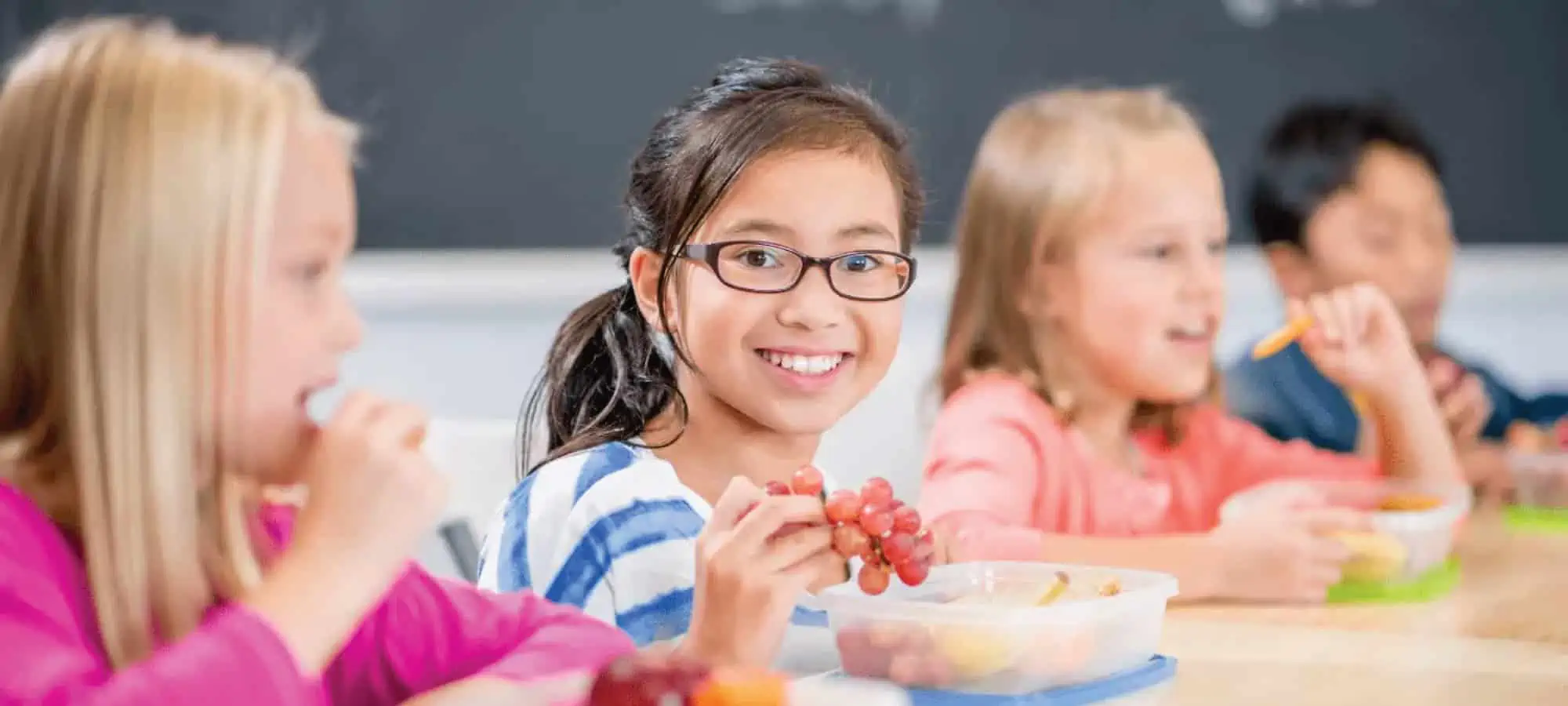 Child at school smiling with grapes
