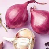 Onion, garlic and leeks on a pink background