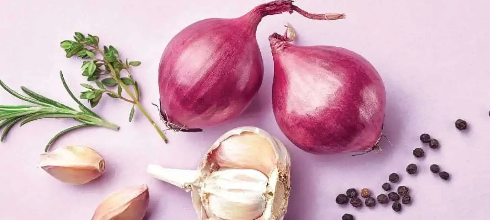 Onion, garlic and leeks on a pink background