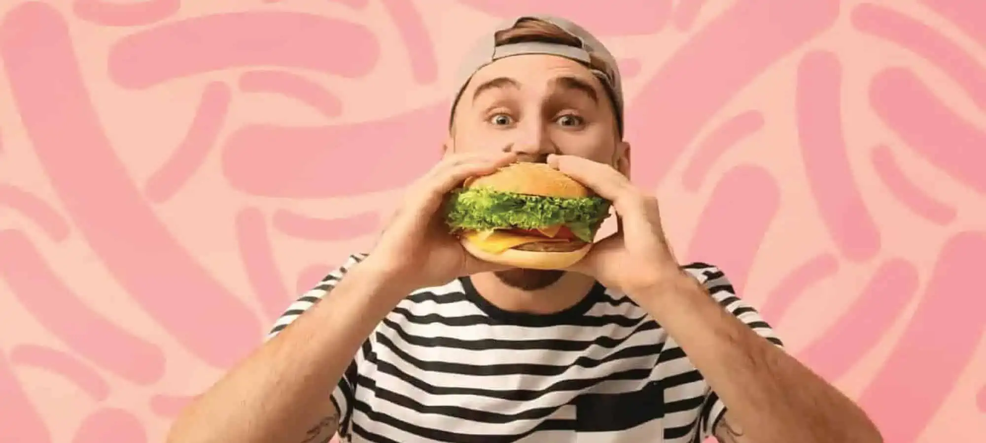 Man eating a burger with pink microbe background