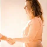 Parent shaking hands with doctor with teenager in the background