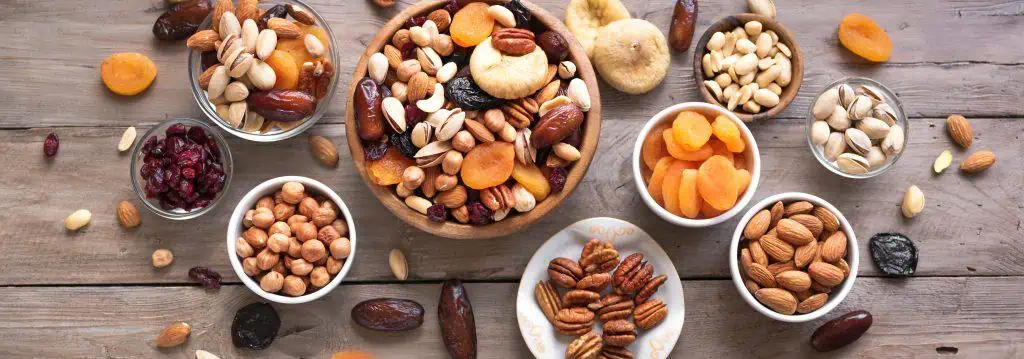 Image de bols remplis de noix, de fruits secs et d'autres en-cas riches en fibres pour illustrer ce qu'il ne faut pas manger dans le cadre d'un régime pauvre en résidus.