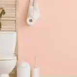 bathroom with toilet, garbage can and hanging toilet paper against pink walls