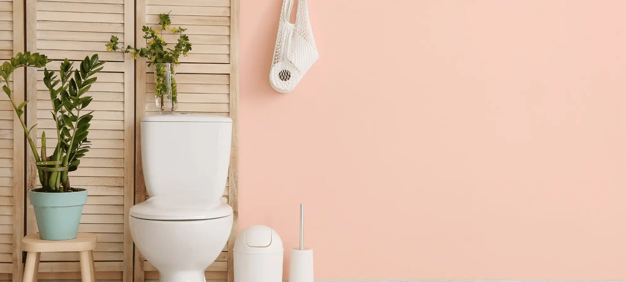 bathroom with toilet, garbage can and hanging toilet paper against pink walls