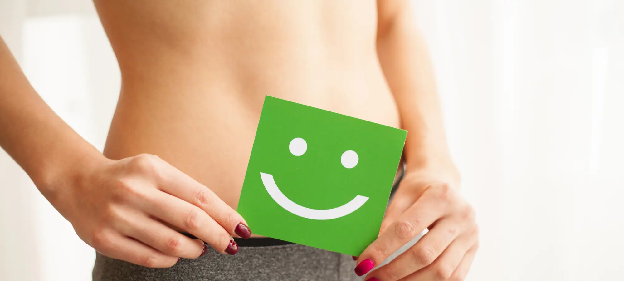 hands holding square photo of a smiley face in front of stomach to 